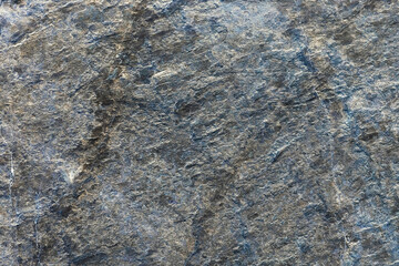 Rough texture of mountain wild stone. Marble. Granite. Stone abstraction. Mountain stone. The rough surface of an ancient mountain. Grunge texture. Laminated surface. Abstract grunge background.