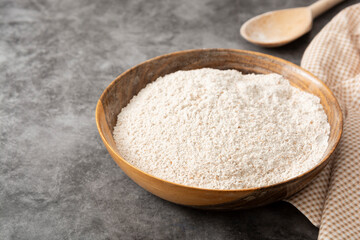 Whole grain flour in wooden bowl. Baking ingredient for pastry and bread.