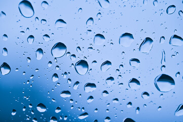 Soft focus rain drops on car glass and light bokeh background view in car.