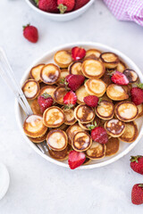 Mini pancakes with strawberries on a light background. Tasty breakfast. Food trending. Baby food