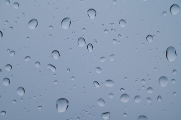 Soft focus rain drops on car glass and light bokeh background view in car.