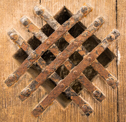 Gitter aus Stahl in einer Holztür als Guckloch.