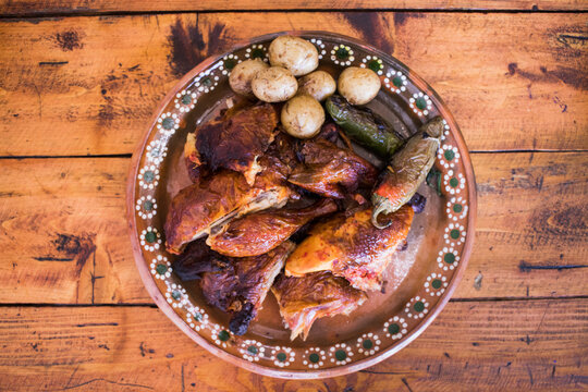 Plato de barro con pollo rostizado, papas cambray y chiles jalape&ntilde;os asados