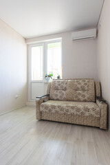 Fragment of the interior of the room for rent, view of the exit to the balcony, sofa and air conditioning