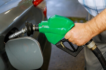 Man pumping gasoline car at gas station being filled with fuel on