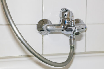 Old fossil bathroom fittings and fossil sanitary with stainless chromed equipment in the restroom for showering or faucet sink shows repair maintenance due to dripping water on chrome wrench