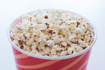 Popcorn in red striped cardboard bucket isolated on white background