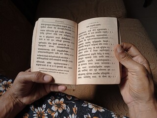 Woman reading old bhagwat Gita in Sanskrit religious book - obrazy, fototapety, plakaty