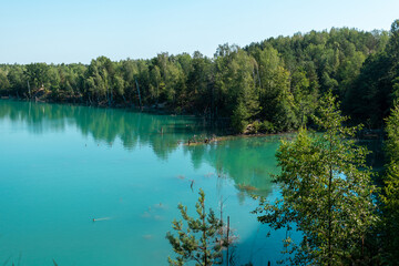 A forest lake on the site of an old quarry with turquoise water. Natural landscape.