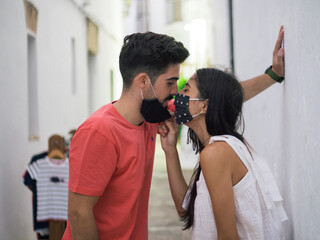 Pareja joven vistiendo mascarilla durante la pandemia del covid-19 demostrando su cariño...