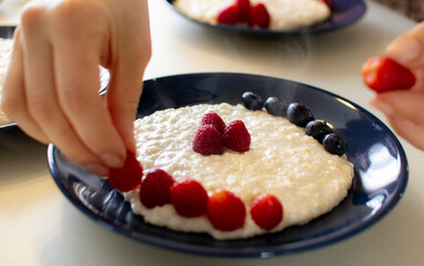 Oatmeal porridge with berries, in a blue plate. Healthy breakfast.