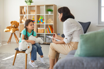 Little girl sharing her concerns with supportive child psychologist during therapy session in