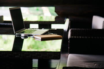 Young slender girl at the restaurant table works behind a laptop