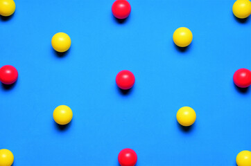 Small colored balls, red and yellow, on a blue background, placed in line, space for text