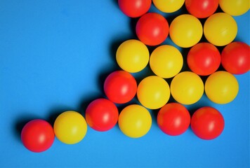 Small colored balls, yellow and red, on a blue background, space for text
