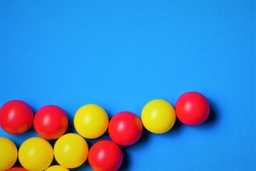 Small colored balls, yellow and red, on a blue background, space for text