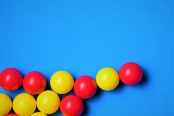Small colored balls, yellow and red, on a blue background, space for text