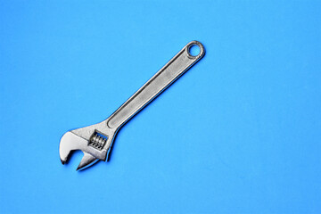 Variable wrench on blue background, space for text