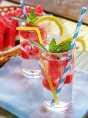 fresh summer cool drink with watermelon slices, mint and lemon on wooden background