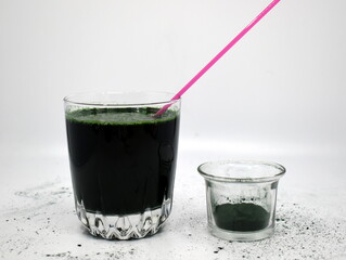 Green spirulina solution and spirulina powder in glass beakers