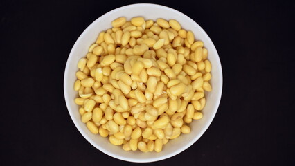 Soybeans after soaking for 24 hours in a bowl on a black background. View from above.
