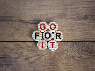 Wooden circles with text 'go for it' on beautiful wooden table. Business concept. Copy space.