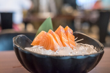 Salmon sashimi with vegetable and ice in a bowl, served in a restaurant