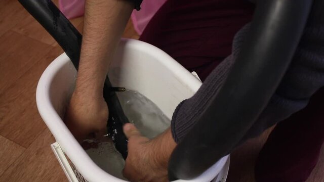 A man is looking for a puncture in a bicycle tube. Lowers her into the water. Air bubbles are visible in the water. He inserts a match into the puncture. Close-up shot.