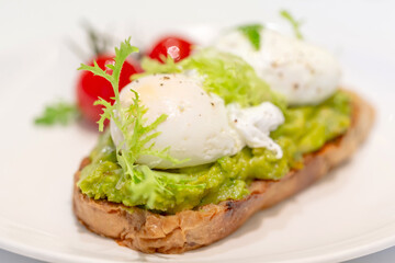 Avocado toast with poached eggs and grilled tomatoes, closeup