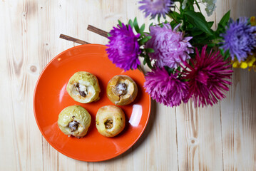 Obraz na płótnie Canvas baked apples with walnut and sugar on orange plate on wooden table with cinnamon and aster flowers