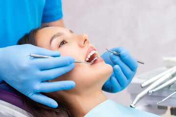 Naklejka premium Attractive young woman in a dental clinic with a male dentist. Healthy teeth concept.