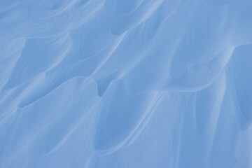 Snow texture. Wind sculpted patterns on snow surface. Wind in the tundra and in the mountains on the surface of the snow sculpts patterns and ridges (sastrugi). Arctic, Polar region. Winter background