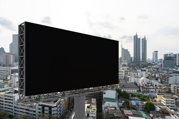 Blank black road billboard with Bangkok cityscape background at day time. Street advertising poster, mock up, 3D rendering. Side view. The concept of marketing communication to promote or sell idea.