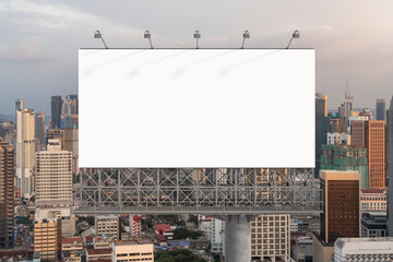 Obraz premium Blank white road billboard with Kuala Lumpur cityscape background at sunset. Street advertising poster, mock up, 3D rendering. Front view.