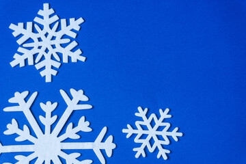 White snowflakes cut from felt on a blue background with copy space. Christmas decoration.
