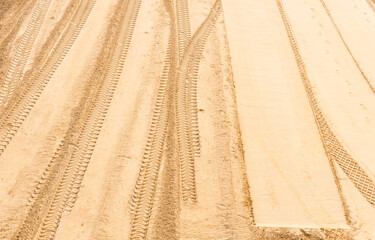 Sand on a construction site with tire marks and footprints. Textured abstract background.