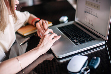 Young slender girl at the restaurant table works behind a laptop