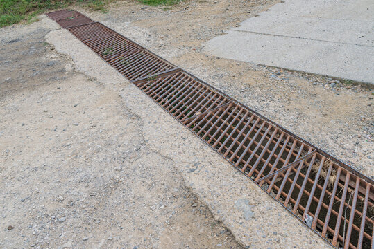Countryside road drainage grate rusty metal steel grid grill with mud 

