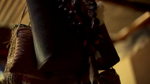 Purse bags and a traditional tribal necklace hang from a post in a village for indigenous people along the Amazon River