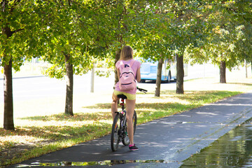 Girl rides a Bicycle in the summer on a city street.
