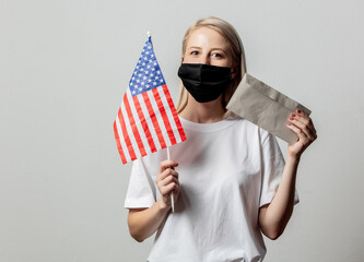 Blonde girl in face mask with USA flag and money on white background