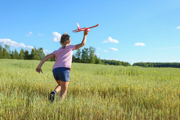 Fototapeta premium cheerful child plays with styrofoam plane in the summer field 