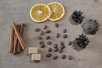 Food composition with coffee, cinnamon sticks, brown sugar, oranges and pine cones on a wooden background. Flatlay. Top view.