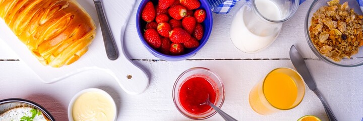 Delicioso Café da manhã com geléia de morango, suco de laranja, cereais e ovo na mesa branca.