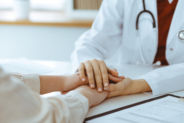 Hands of unknown woman-doctor reassuring her female patient, close-up. Medicine concept