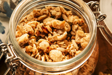 Homemade granola with nuts and seeds in glass jar on a wooden background for healthy breakfast. Close up