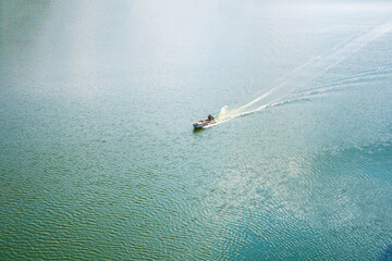A lonely fishing boat sails among the blue sea. View from above
