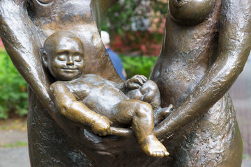 Fototapeta na wymiar Sculpture of a happy sleeping child in the arms of parents. Monument to family and children.