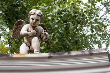 Little white cupid statue sitting on the roof. Old sculpture