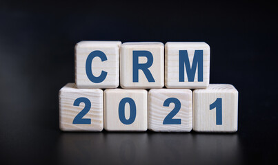 CRM 2021 text on wooden cubes on a black background with reflection.